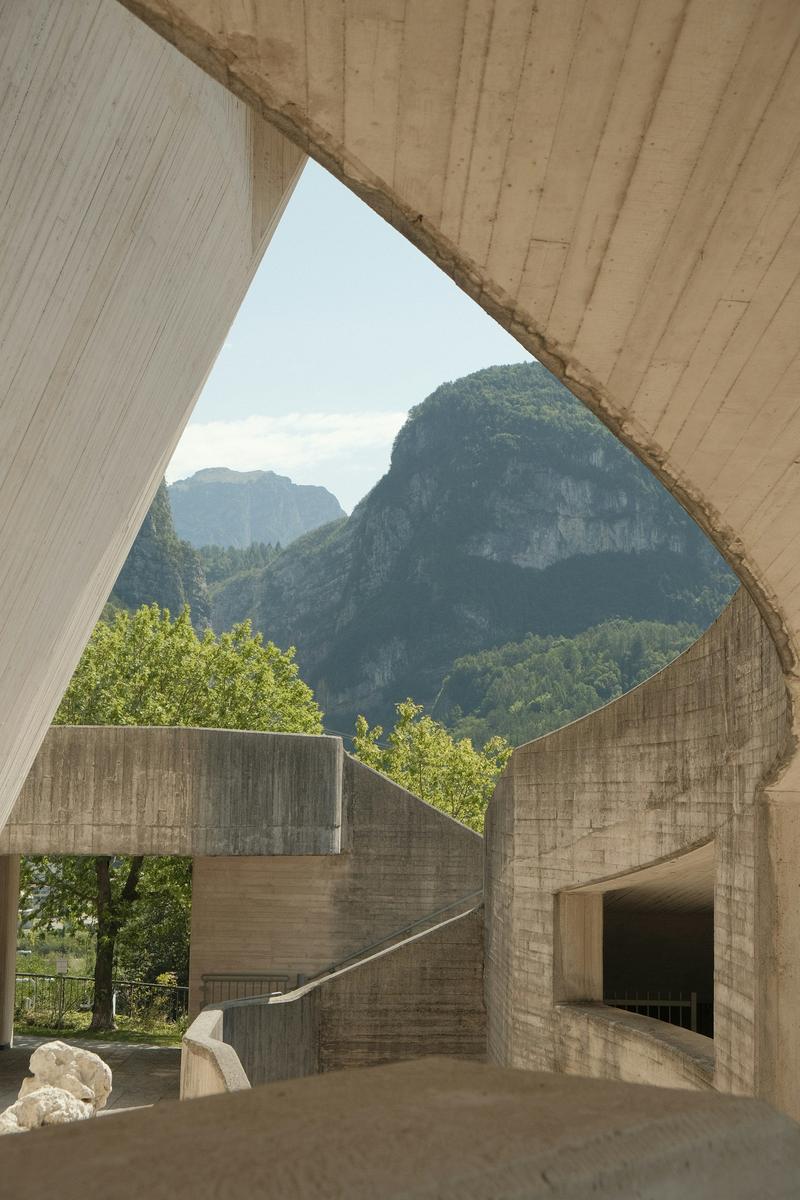 Curved concrete architecture framing green mountains
